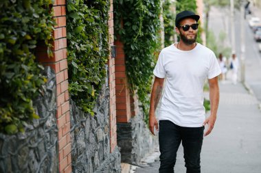 Sakallı, beyaz, boş tişörtlü, beysbol şapkalı, logonuz için yeri olan yakışıklı bir hippi mankeni.