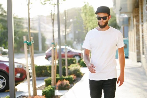 Hipster gutaussehendes männliches Model mit Bart trägt weißes Blank-T-Shirt und Baseballmütze mit Platz für Ihr Logo oder Design im lässigen urbanen Stil — Stockfoto