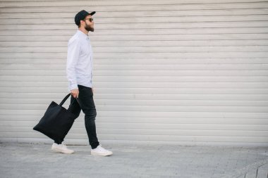 Kentsel şehir arka plan karşı siyah tekstil eko çanta tutan genç adam. . Ekoloji veya çevre koruma kavramı. Tasarım veya logo sahte için siyah eko çanta