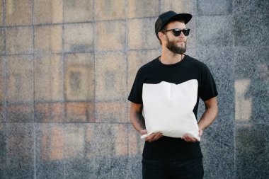 Kentsel şehir arka plan karşı beyaz tekstil eko çanta tutan genç adam. . Ekoloji veya çevre koruma kavramı. Sahte için beyaz eko çanta.