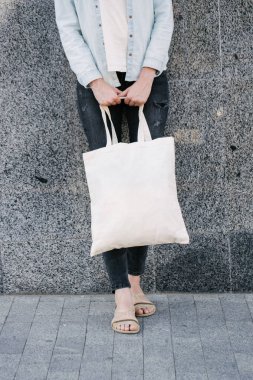 Kentsel şehir arka plan karşı beyaz tekstil eko çanta tutan kadın. . Ekoloji veya çevre koruma kavramı. Sahte için beyaz eko çanta.