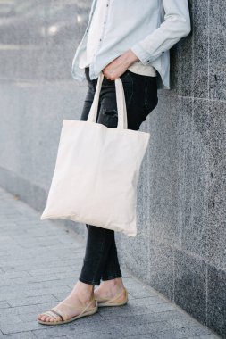 Kentsel şehir arka plan karşı beyaz tekstil eko çanta tutan kadın. . Ekoloji veya çevre koruma kavramı. Sahte için beyaz eko çanta.