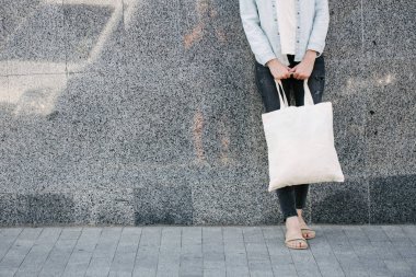 Kentsel şehir arka plan karşı beyaz tekstil eko çanta tutan kadın. . Ekoloji veya çevre koruma kavramı. Sahte için beyaz eko çanta.