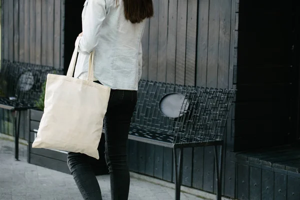 Nő gazdaság fehér textil Eco táska ellen városi város háttérben. . Ökológiai vagy környezetvédelmi koncepció. Fehér öko táska a modell fel. — Stock Fotó