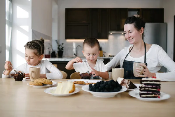 Moeder met kinderen drinken warme chocolademelk en Latte thuis keuken. Ze glimlachen en plezier hebben. Motherhood concept — Stockfoto