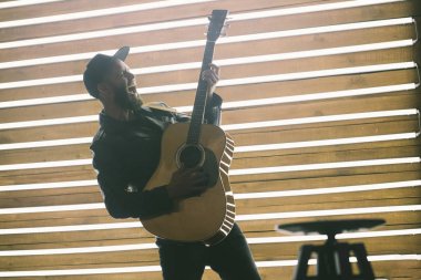 Şarkıcı ve gitarist neon ışıkları ile bir sahnede şarkı. O bir rockçı ve o deri bisikletçi ceket veya siyah kap, kot pantolon ile asimetrik zip ceket giyiyor.