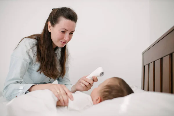 La donna misura la temperatura. Il bambino è malato sdraiato a letto — Foto Stock