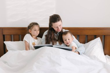 Anne ve çocuk yas yatakta bir kitap okuma