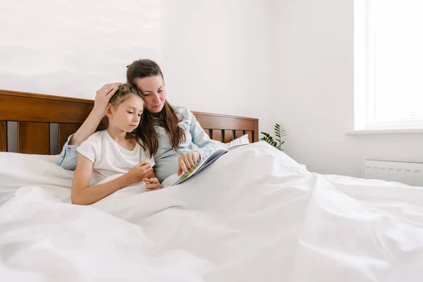 Mãe e filho lendo um livro na cama no luto — Fotografia de Stock