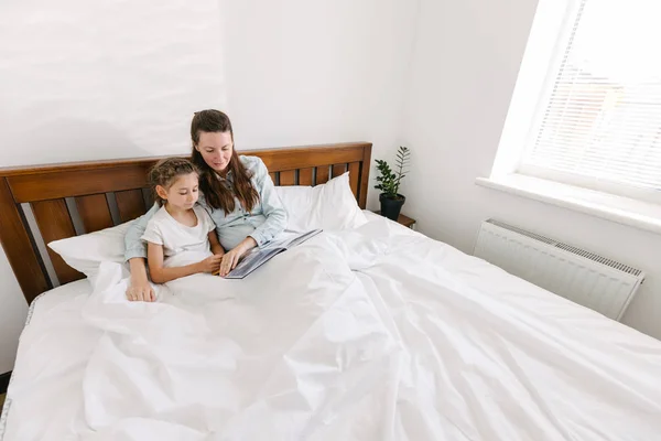 Mãe e filho lendo um livro na cama no luto — Fotografia de Stock