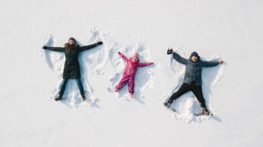 Aile kar meleği yapıyor. Havadan görünüm. Anne ve baba ve chilren bir kar melek yapma