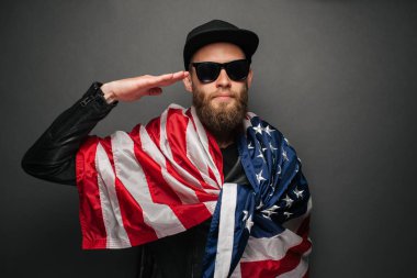 Şehir sokaklarında hipster yakışıklı adam Neon işaretler tarafından aydınlatılmış olmak. O siyah kap, kot pantolon ve güneş gözlüğü ile deri motosikletçi ceket veya asimetrik fermuar ceket giyiyor.