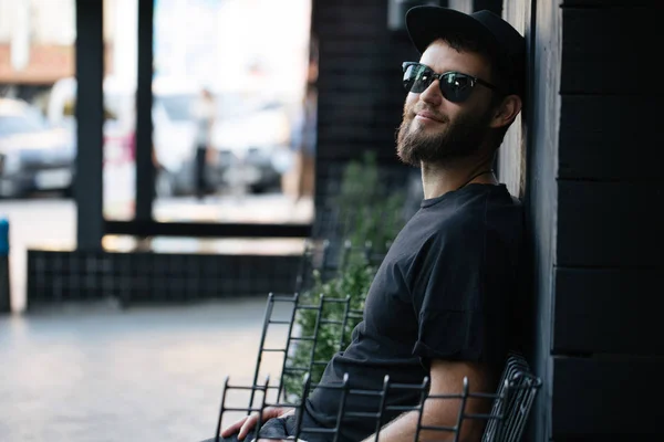 Cantor e guitarrista cantando em um palco. Ele é um roqueiro e ele está vestindo jaqueta de couro motociclista ou jaqueta zip assimétrica com boné preto, jeans . — Fotografia de Stock