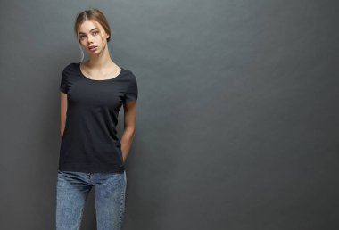 Seksi kadın veya kız logosu için alan ile siyah boş t-shirt giyen, gri arka plan üzerinde rahat kentsel tarzda alay veya tasarım