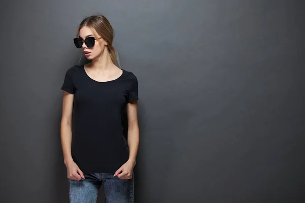 Sexy woman or girl wearing black blank t-shirt with space for your logo, mock up or design in casual urban style over gray background