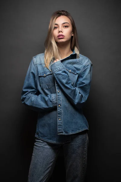 Menina loira sexy vestindo roupas jeans sobre fundo cinza — Fotografia de Stock