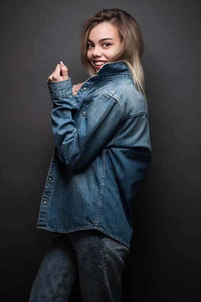 Sexig blond tjej klädd i jeans kläder över grå bakgrund — Stockfoto