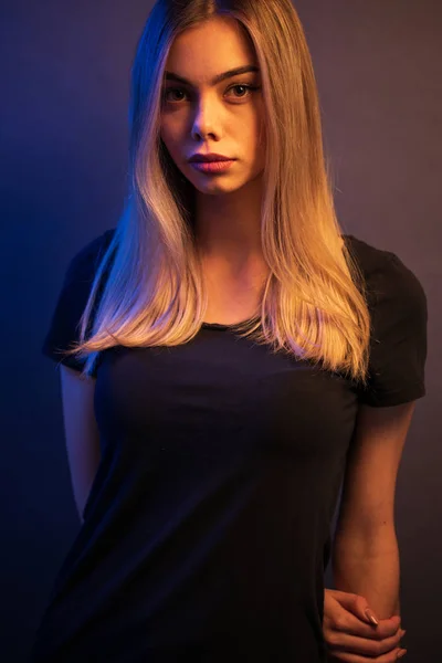 Sexy mladá blondýnka na výšku přes šedý papír v neonové světelné barvě — Stock fotografie