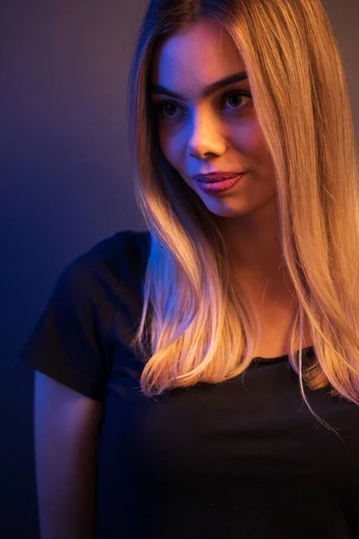 Sexig ung blond flicka porträtt över grå papper bakgrund i neonljus — Stockfoto
