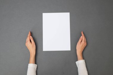 Metnin için beyaz kağıt. Gri dokunun üzerinde boş bir kağıt tutan kadın. Genel Görünüm
