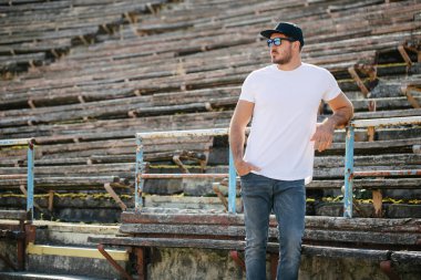 Sakallı, beyaz, boş tişörtlü, beysbol şapkalı, logonuz için yeri olan yakışıklı bir hippi mankeni.