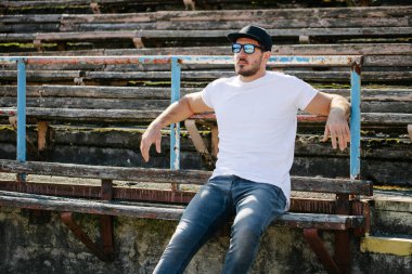 Sakallı, beyaz, boş tişörtlü, beysbol şapkalı, logonuz için yeri olan yakışıklı bir hippi mankeni.