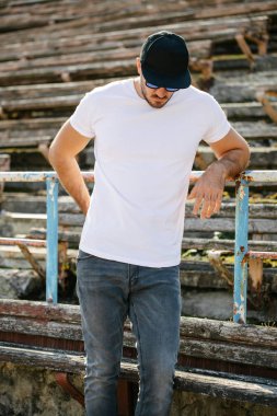 Sakallı, beyaz, boş tişörtlü, beysbol şapkalı, logonuz için yeri olan yakışıklı bir hippi mankeni.