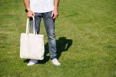 Kentsel şehir arka plan karşı beyaz tekstil eko çanta tutan genç adam. Ekoloji veya çevre koruma kavramı. Sahte için beyaz eko çanta.