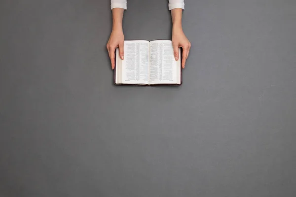 Жінка читає Біблію над сірим столом. Накладне зображення — стокове фото
