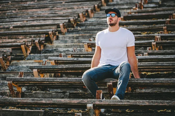 Modelo masculino bonito Hipster com barba vestindo t-shirt branca em branco e um boné de beisebol com espaço para o seu logotipo ou design em estilo urbano casual — Fotografia de Stock