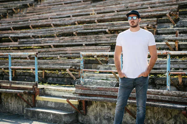 Hipster beau modèle masculin avec barbe portant un t-shirt blanc et une casquette de baseball avec de l'espace pour votre logo ou design dans un style urbain décontracté — Photo