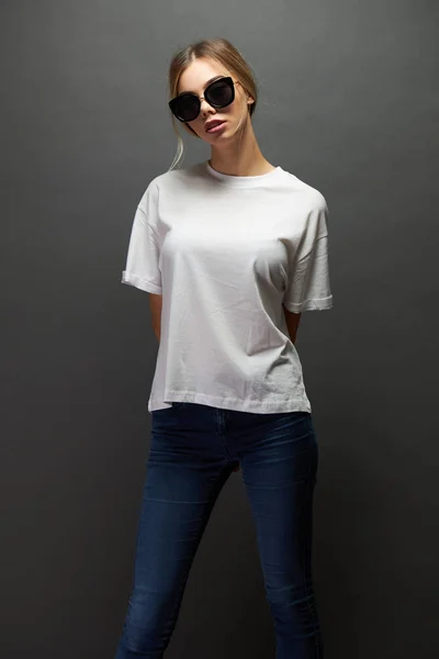 Сексуальная женщина или девушка в белой пустой футболке с местом для логотипа, макет или дизайн на сером фоне — стоковое фото