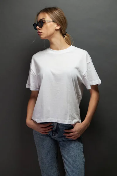 흰색빈 티셔츠를 입고 로고를 쓸 공간 이 있는 섹시 한 여자나 여자, 회색 배경 위에서 사진을 찍거나 디자인을 하거나 — 스톡 사진