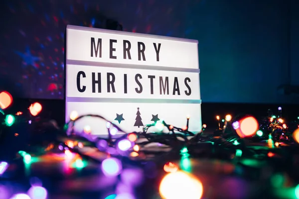 暗闇の中でクリスマスのガーランドライトの上にライトボックスでメリークリスマスサイン — ストック写真