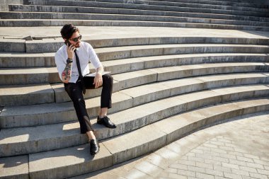 Yakışıklı iş adamı bir telefon görüşmesi yapıyor ya da dışarıda telefon kullanıyor.