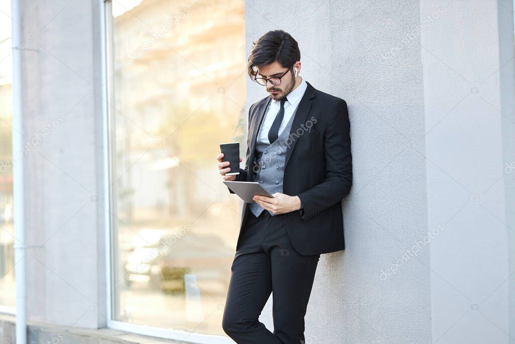 Young Businessman using a tablet pc outside wearing a classic suit