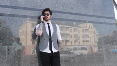 Şehir caddesinde, üzerinde şık giysiler olan bir iş adamı telefonda konuşuyor.