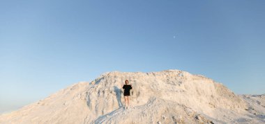 Gün batımında ince, güzel bir kız beyaz dağın üzerinden yazın güneşe bakıyor.