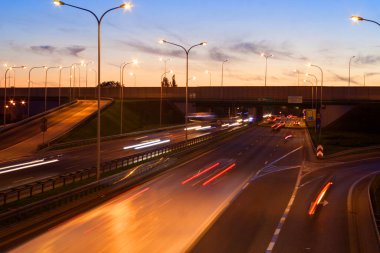 Varşova şehir otobanındaki arabaların ışık çizgileri. Akşam trafiği. Sıcak yaz akşamı ve açık mavi gökyüzü