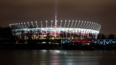 Polonya 'nın Varşova kentindeki Vistula nehri üzerinde Ulusal Stadyum (Stadion Narodowy) ile gece manzarası