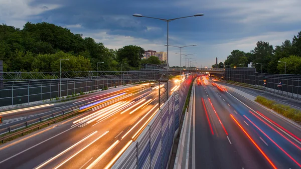 Varşova şehir otobanındaki arabaların ışık çizgileri. Akşam trafiği. Sıcak yaz akşamı ve açık mavi gökyüzü