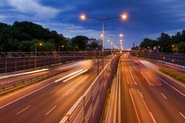 Varşova şehir otobanındaki arabaların ışık çizgileri. Akşam trafiği. Sıcak yaz akşamı ve açık mavi gökyüzü