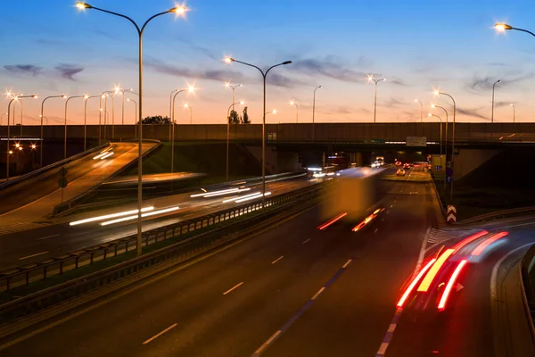 Varşova şehir otobanındaki arabaların ışık çizgileri. Akşam trafiği. Sıcak yaz akşamı ve açık mavi gökyüzü