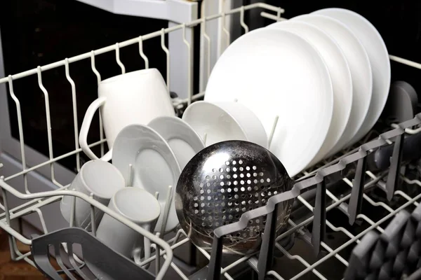 Dishwasher in the kitchen loaded with clean white dishes