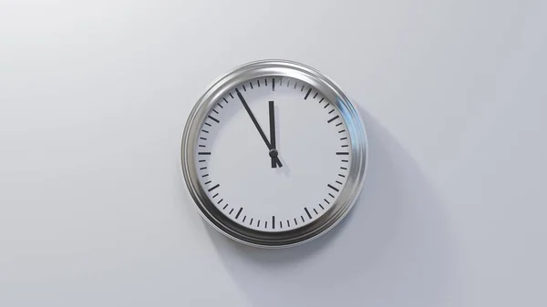 Glossy chrome clock on a white wall at five to zero. The time is 11:55 or 23:55
