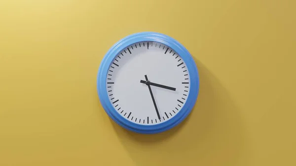 橙色墙上的一个光滑的蓝色钟 三点二十七分 时间是03 27或15 — 图库照片