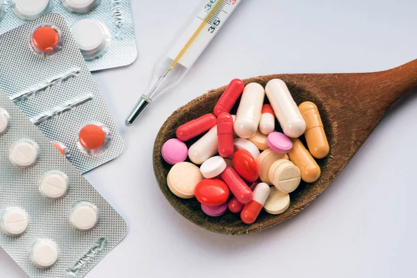 Tablet hastalıklarının tedavisi için bir sürü bir masada evde dağılmışlardır. Masadaki diğer ilaçlar. Vitaminler bir masada evde. Hastanın ısısını ölçmek için termometre