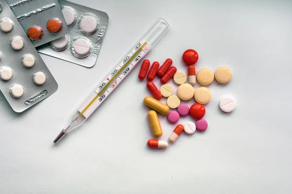Tablet hastalıklarının tedavisi için bir sürü bir masada evde dağılmışlardır. Masadaki diğer ilaçlar. Vitaminler bir masada evde. Hastanın ısısını ölçmek için termometre