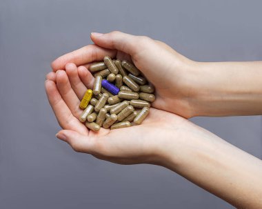 Kadınların elinde renksiz yüzsüz kapsüller arasında iki parlak kapsül vardır. Kavramsal yakın plan fotoğraf. Herkes gibi olma. Kendin ol. Sağlıklı bir yaşam tarzı. Seçim yap