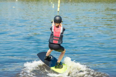 Spor koruyucu giysili 13 yaşındaki bir genç kızın fotoğrafı ve Wake Park 'ta kask eğitimi. Su sporu. Gençlerin boş vakitleri ve hobileri. - Güvenlik. Yaz kampı. Sağlıklı bir yaşam tarzı. Tatil